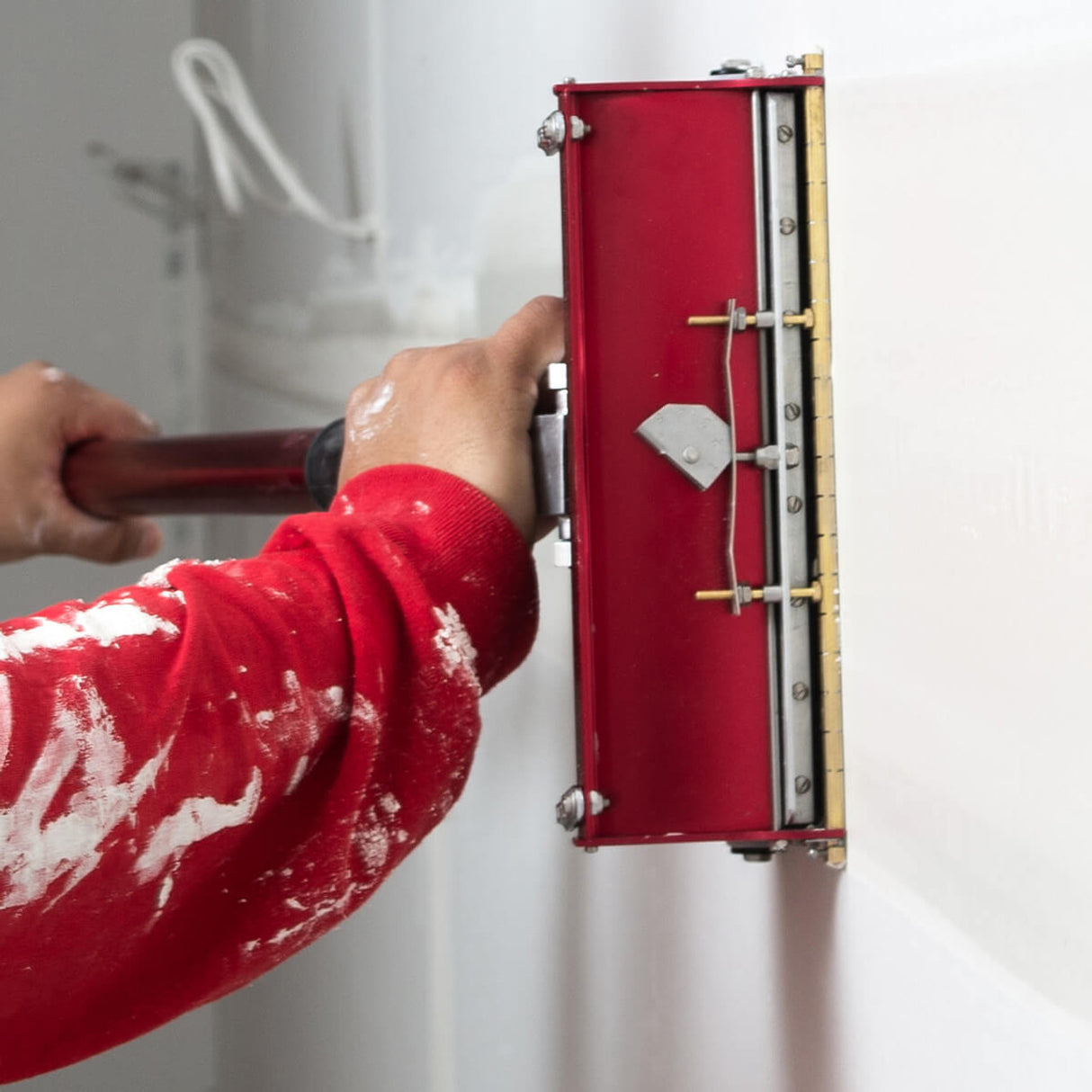 Person running a red Level 5 flat box attached to a Level 5 extenedable flat box handle across a wall joint