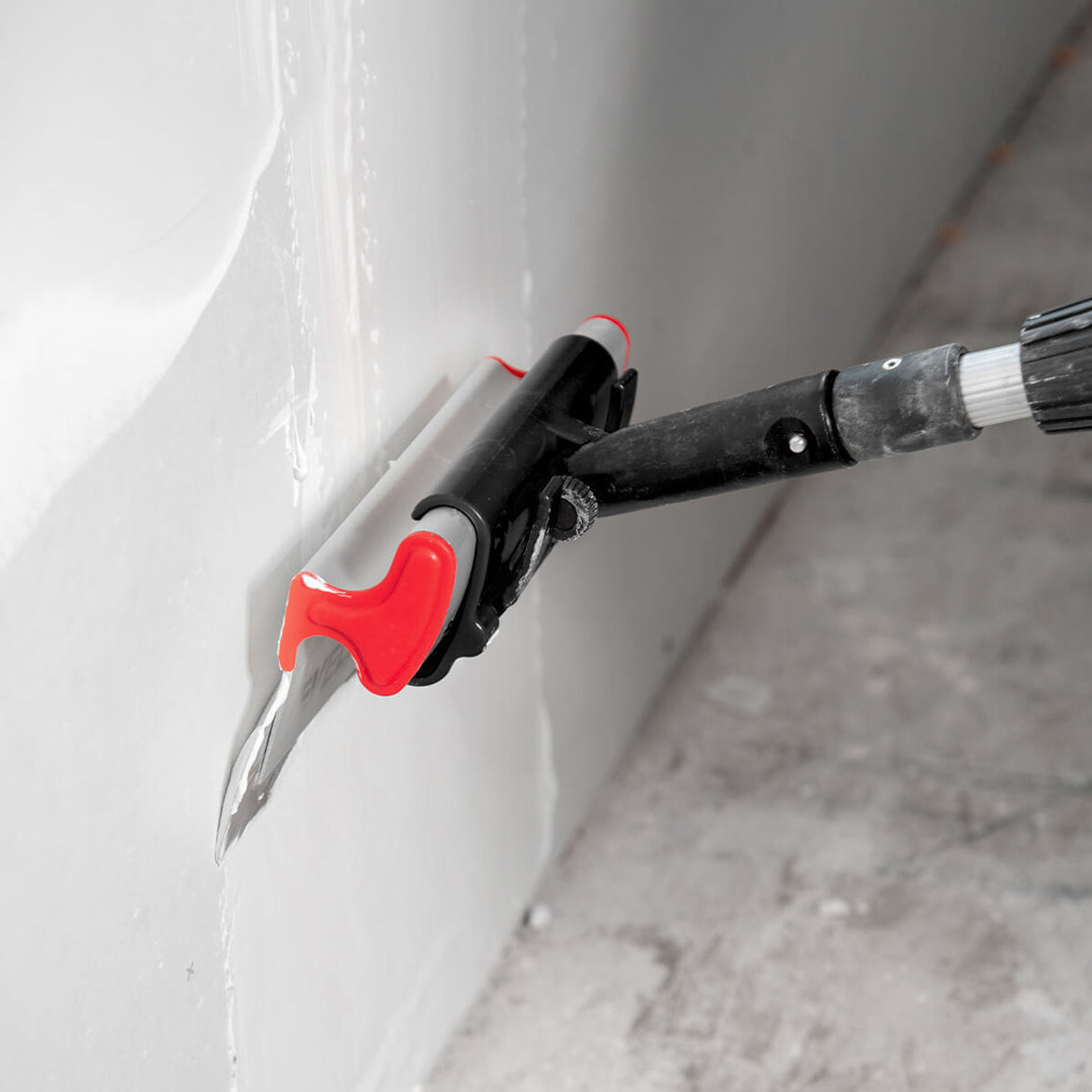 Level 5 skimming blade pole adaptor attached to a painter’s pole, holding a Level 5 smoothing blade feathering a mud coat on a joint